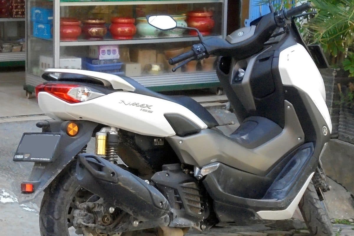 Настоящий белый скутер Yamaha NMAX 155 на улице, на кузове виден шильдик модели