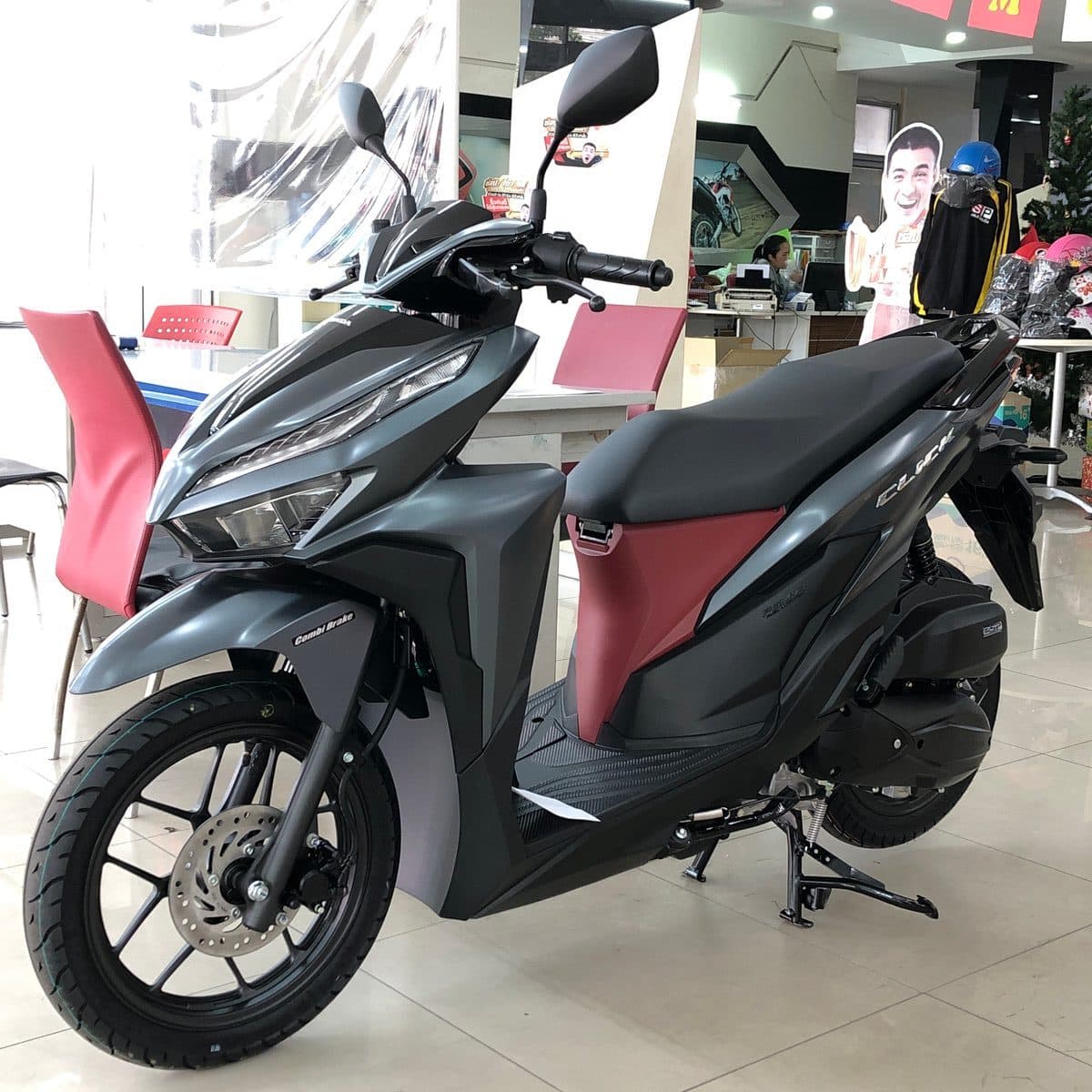 Honda Click 125 синего цвета, вид сбоку, на парковке в Таиланде.